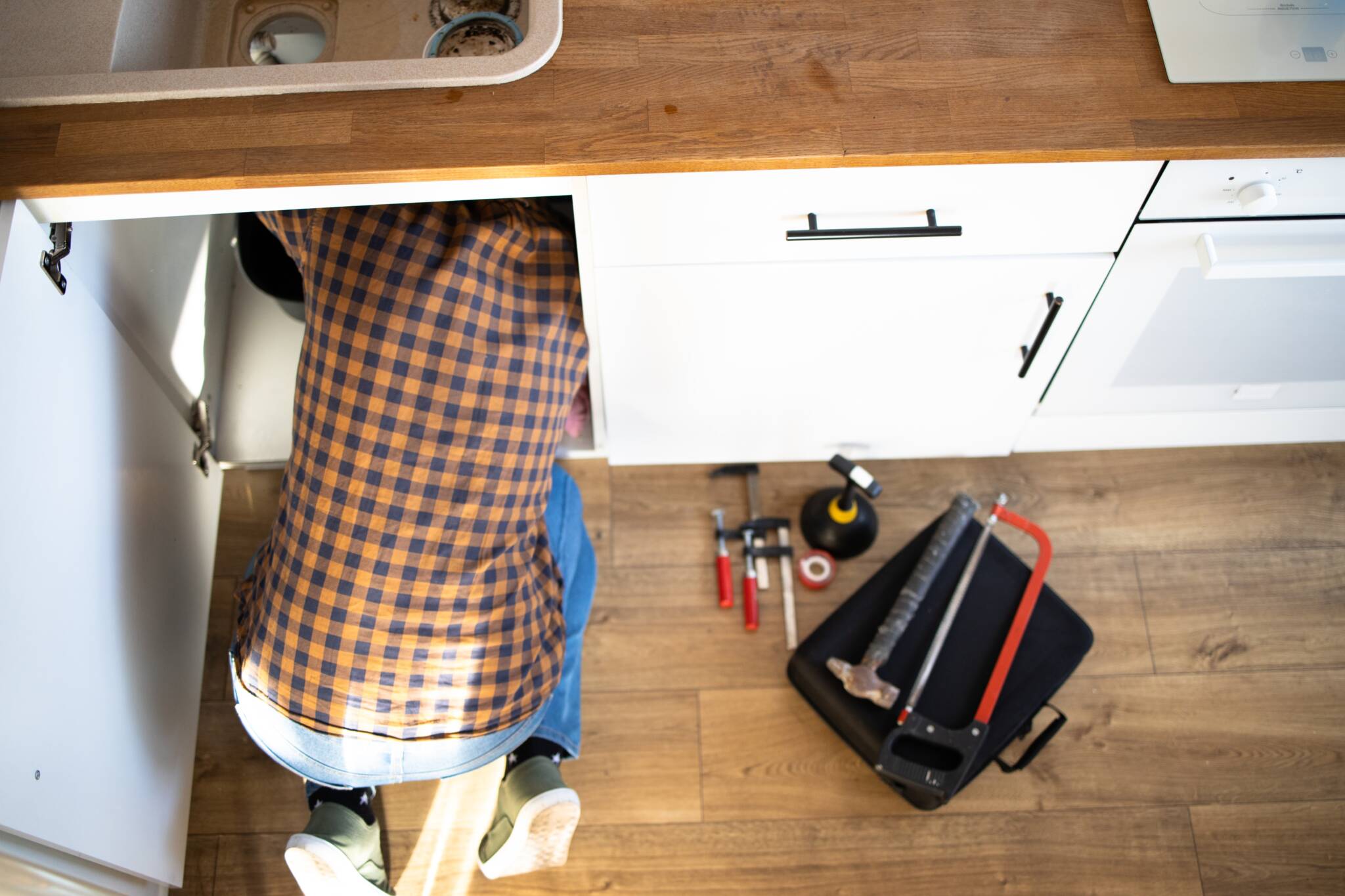 Plumber,repairs,plumbing,pipes,in,kitchen,sink.,removing,blockage,clog
