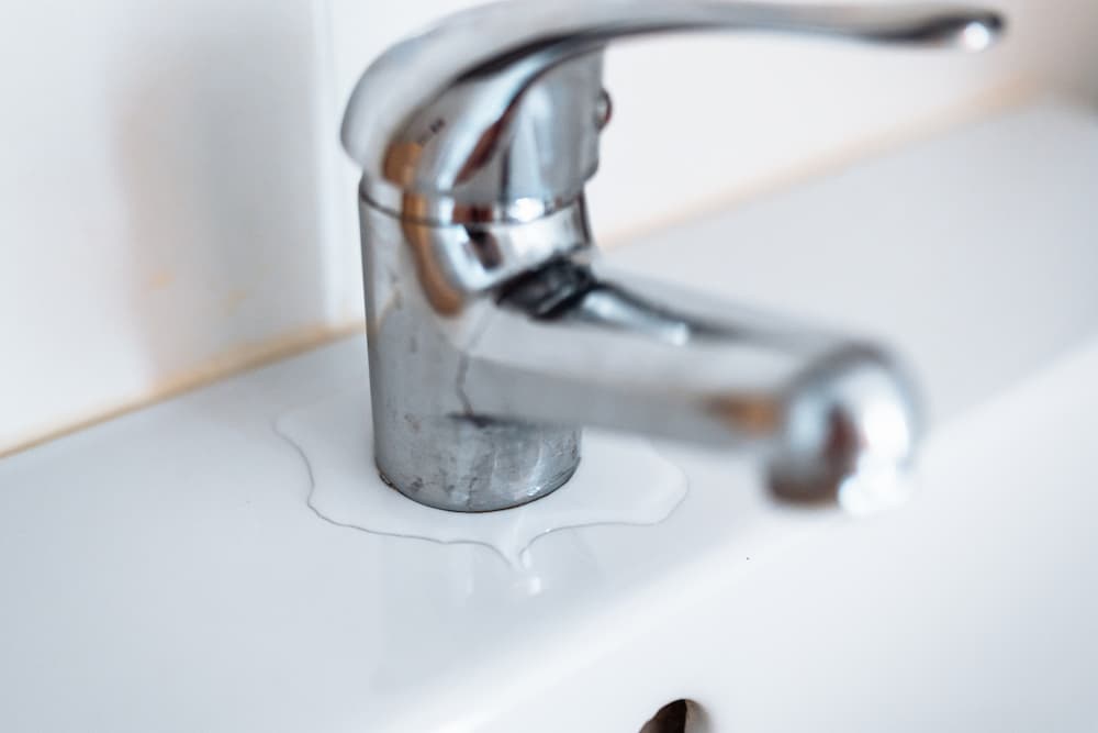 Water pooling around the sink faucet, illustrating a common plumbing emergency or leak that requires the best plumbing service.